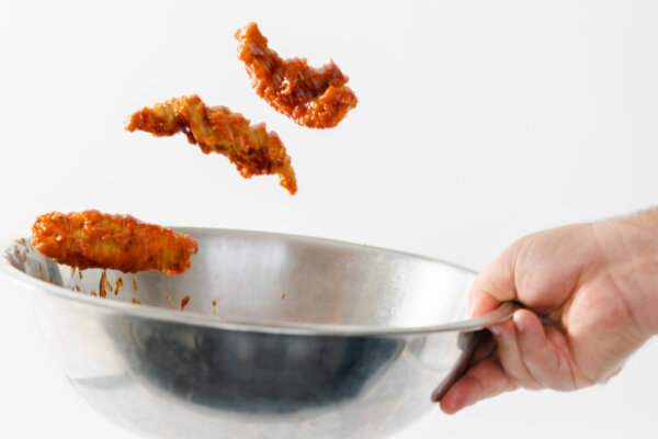 Griffith chef tossing chicken tenders in a hot sauce