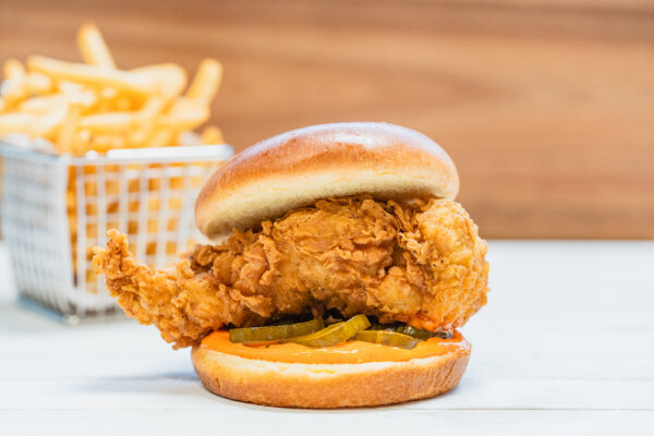 Crispy chicken sandwich with french fries in the background