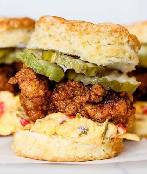 Nashville hot chicken sliders on homemade flaky biscuits with pimento cheese and dill pickles.