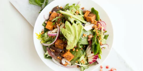 A salad topped with avocado and a plant-based protein.