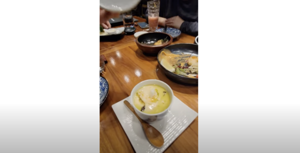 A Japanese Chawanmushi in a ramekin on a table full of other traditional Japanese food.