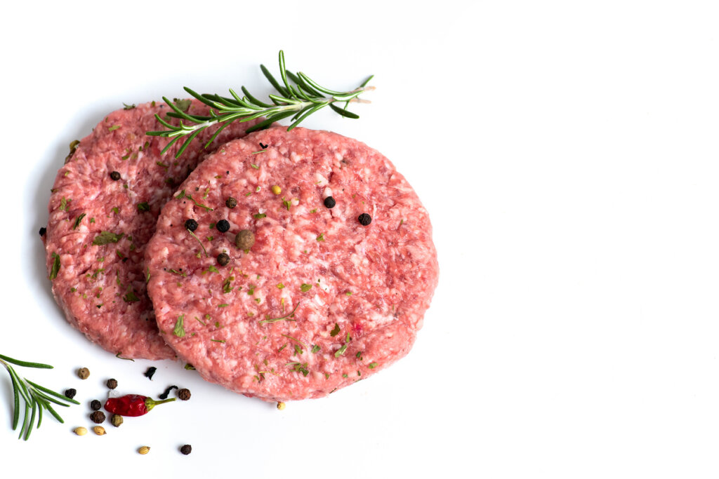 Two raw beef burgers on a white background, showcasing fresh hamburger meat ready for cooking