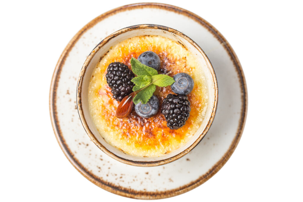 Single-serve crème brûlée dessert with caramelized top and blueberries, baked to perfection