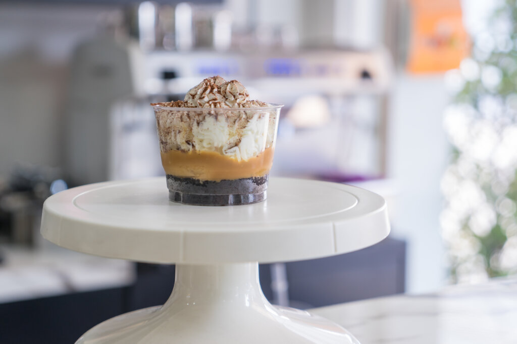 Individual Banoffee dessert cups on a cake turntable in a café setting, highlighting single-serve indulgent treats.