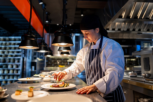 Chef plating a dish in a professional kitchen, illustrating how traditional flavors are refined and adapted for modern foodservice experiences.
