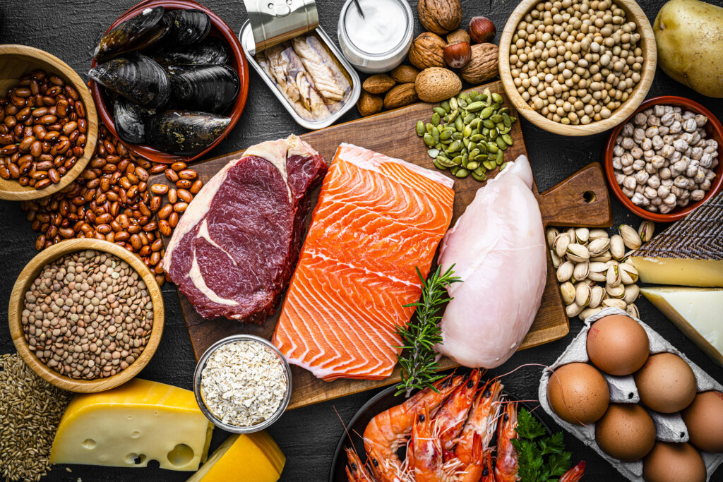 Assorted high-protein foods including eggs, beans, nuts, and lean meats arranged on a table, representing healthy protein sources for balanced nutrition.