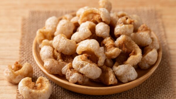 Bowl of crispy puffed snacks on a wooden surface, representing Thai curry-inspired flavors with aromatic spices and savory seasoning.