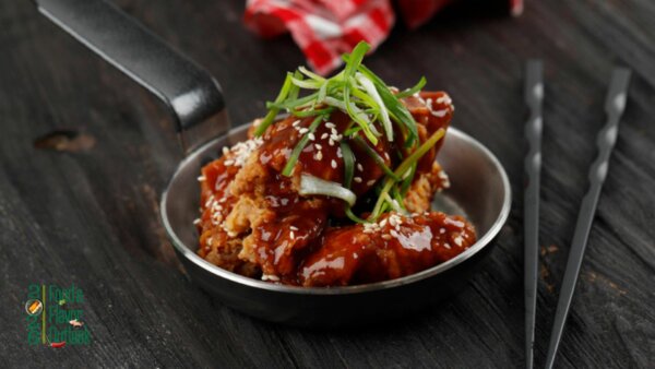 Bowl of crispy chicken nuggets coated in Korean BBQ sauce and garnished with sesame seeds and green onions, showcasing the growing popularity of Korean-inspired flavors.