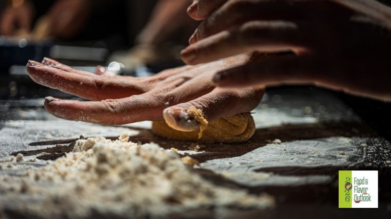 Hands shaping dough on a flour-covered surface during traditional food preparation, representing recognizable ingredients in food industries.