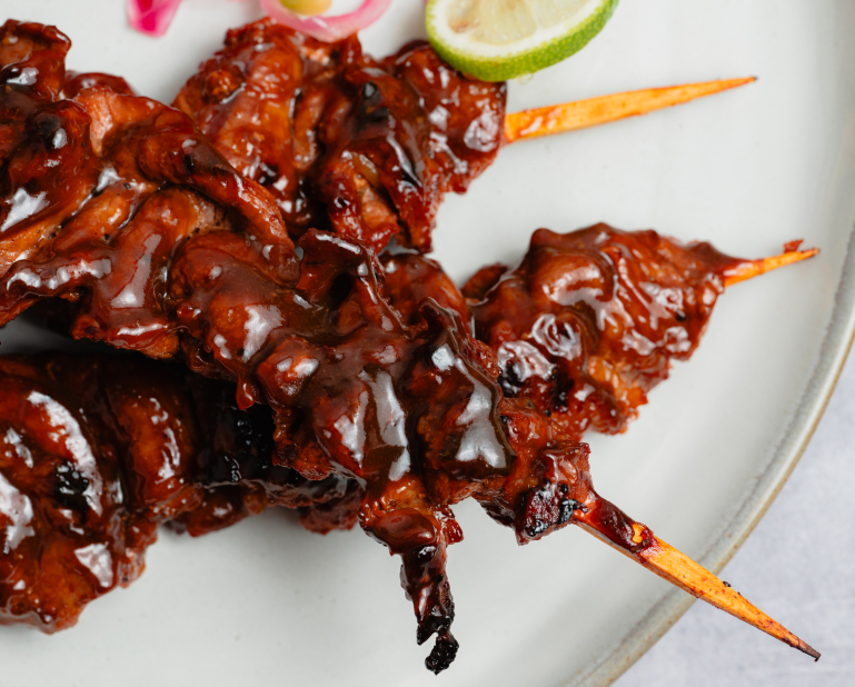 Glazed skewers served with a side of lime.